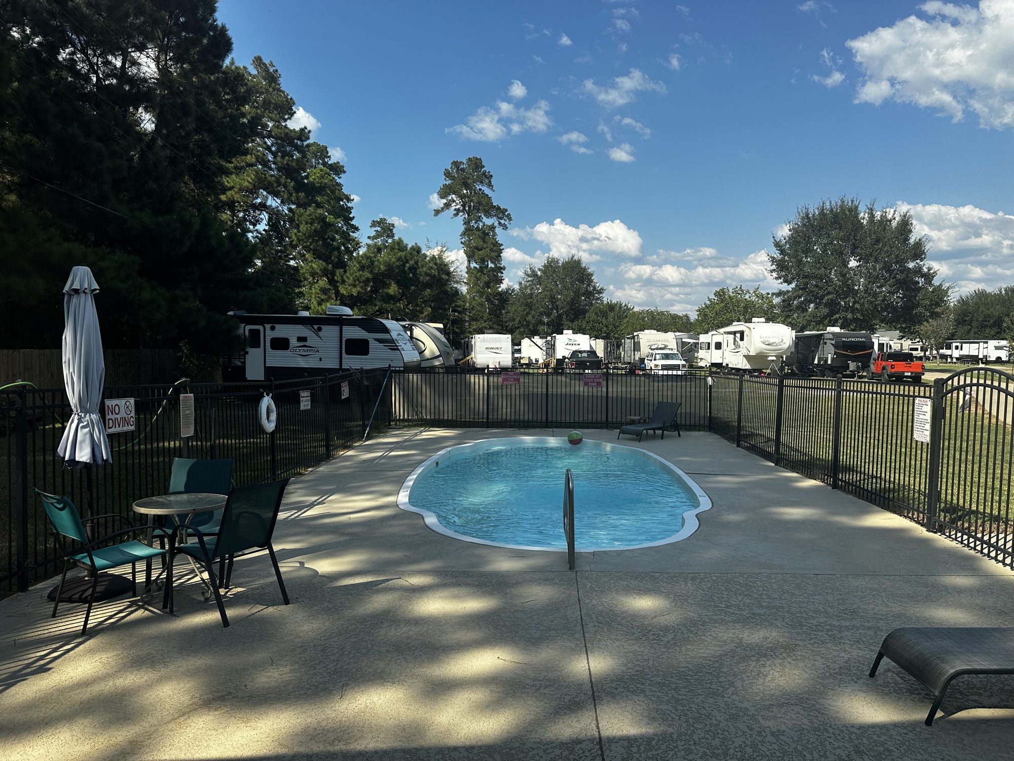 Fenced swimming pool with lounge chairs and umbrella